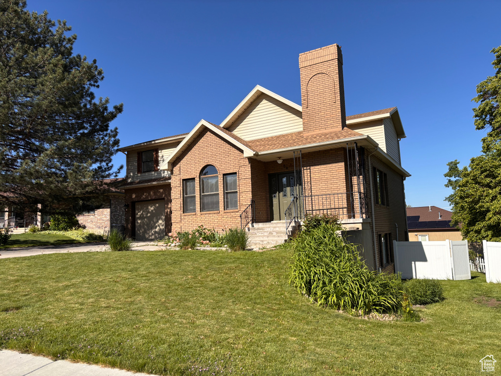 View of front facade with a garage, brick siding, a chimney, and driveway