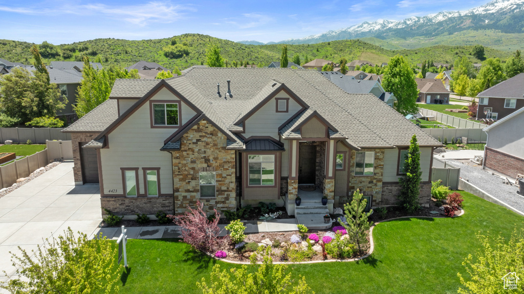 View of front of house with concrete driveway, stone siding, a mountain view, and a residential view