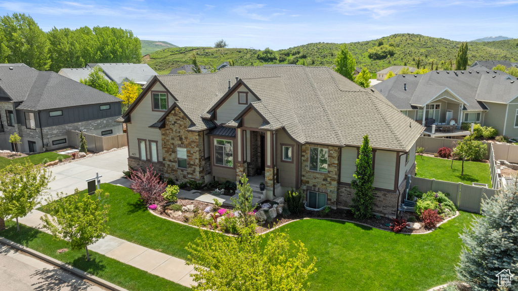 View of front of home with concrete driveway, stone siding, a mountain view, and a residential view