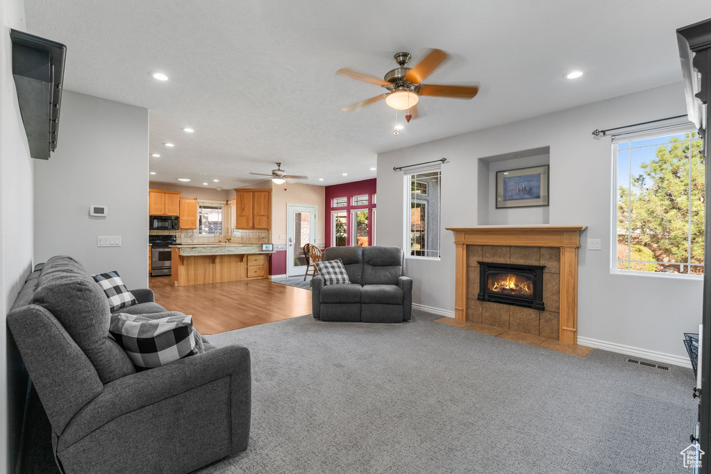Living area with a ceiling fan, visible vents, recessed lighting, and a fireplace
