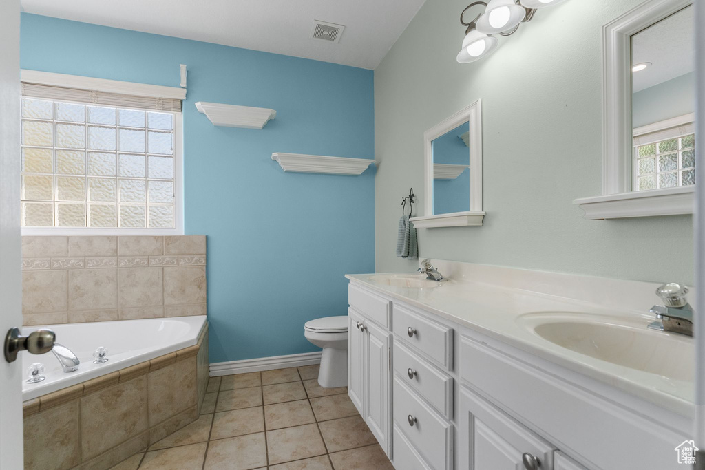 Full bath with visible vents, toilet, a sink, a bath, and baseboards