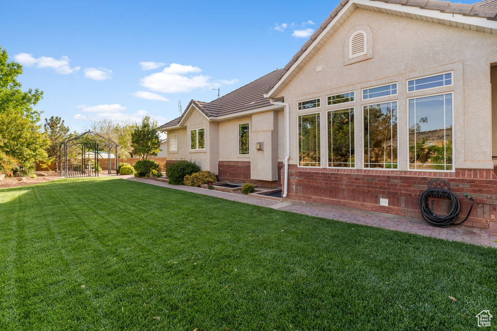 Back of property featuring a tile roof, a gazebo, and stucco siding