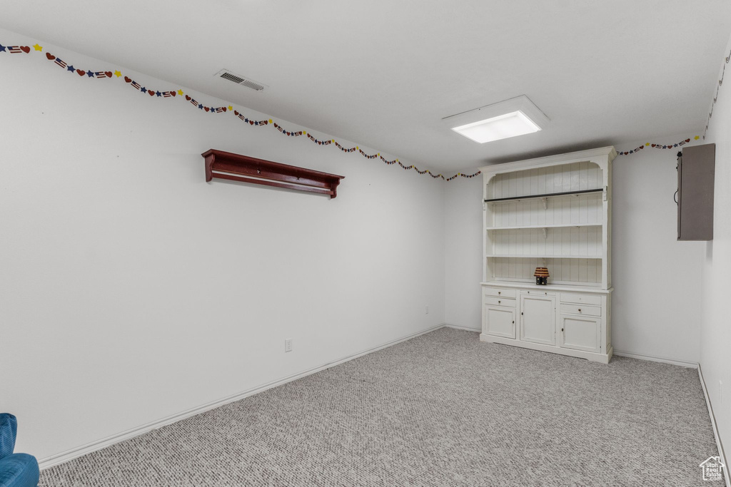 Interior space featuring electric panel, baseboards, visible vents, and light colored carpet