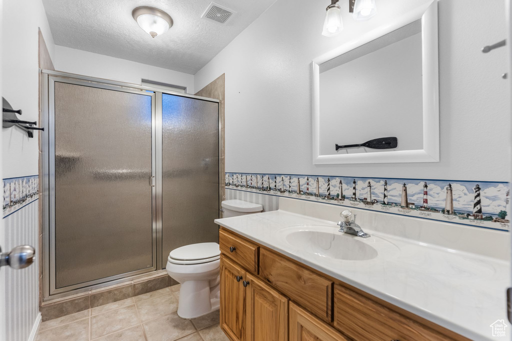 Bathroom featuring toilet, tile patterned flooring, visible vents, and a stall shower