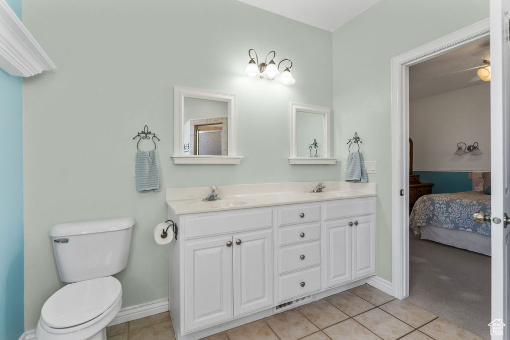 Ensuite bathroom featuring connected bathroom, tile patterned floors, toilet, and a sink