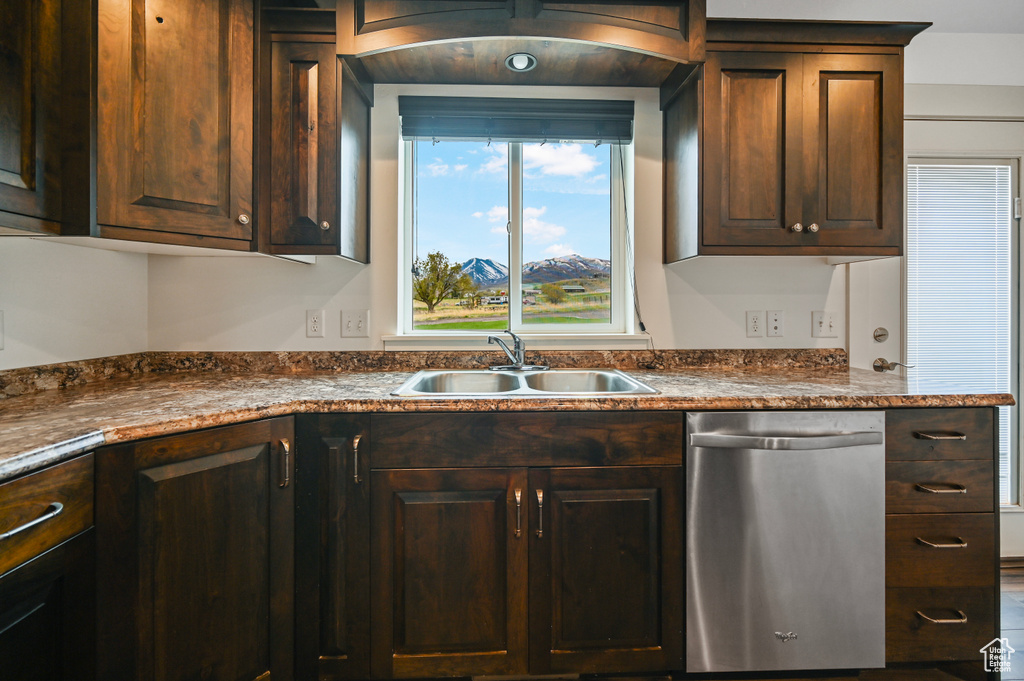 Kitchen with a sink, dishwasher, dark brown cabinetry, and dark countertops