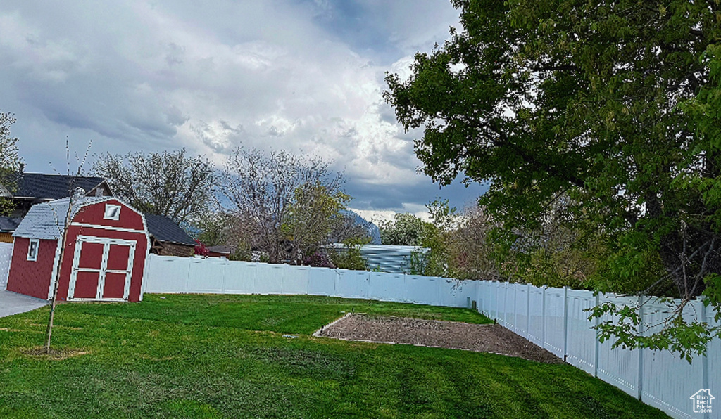 View of yard featuring a storage shed, an outbuilding, and a fenced backyard