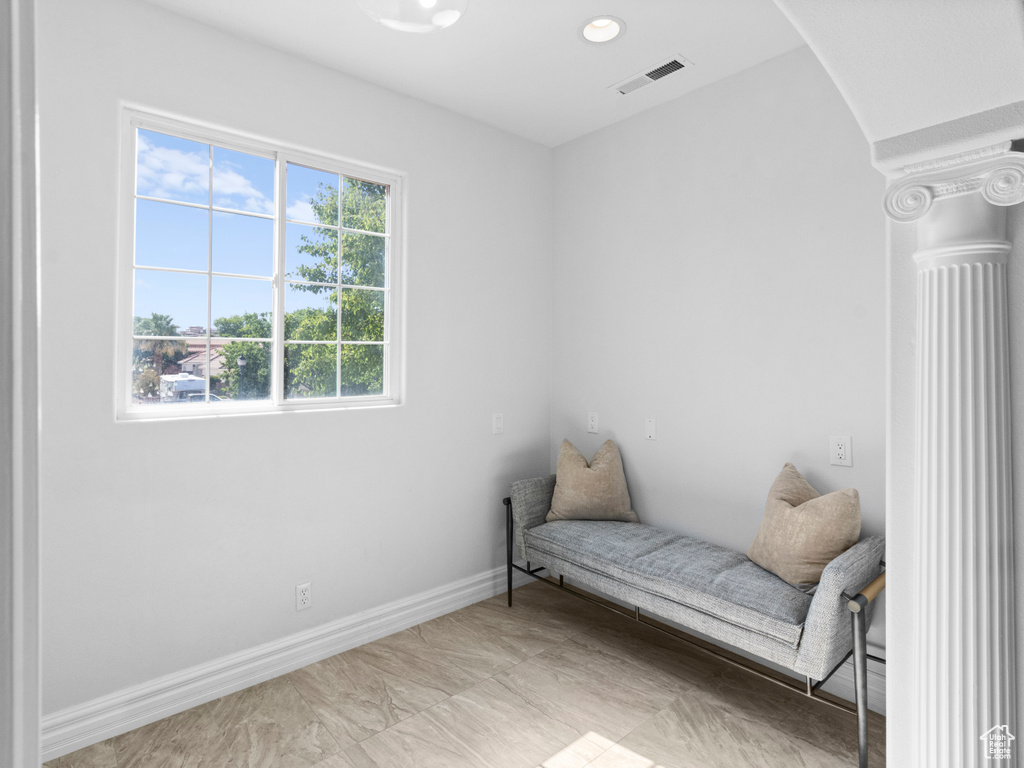 Living area with arched walkways, decorative columns, visible vents, and baseboards