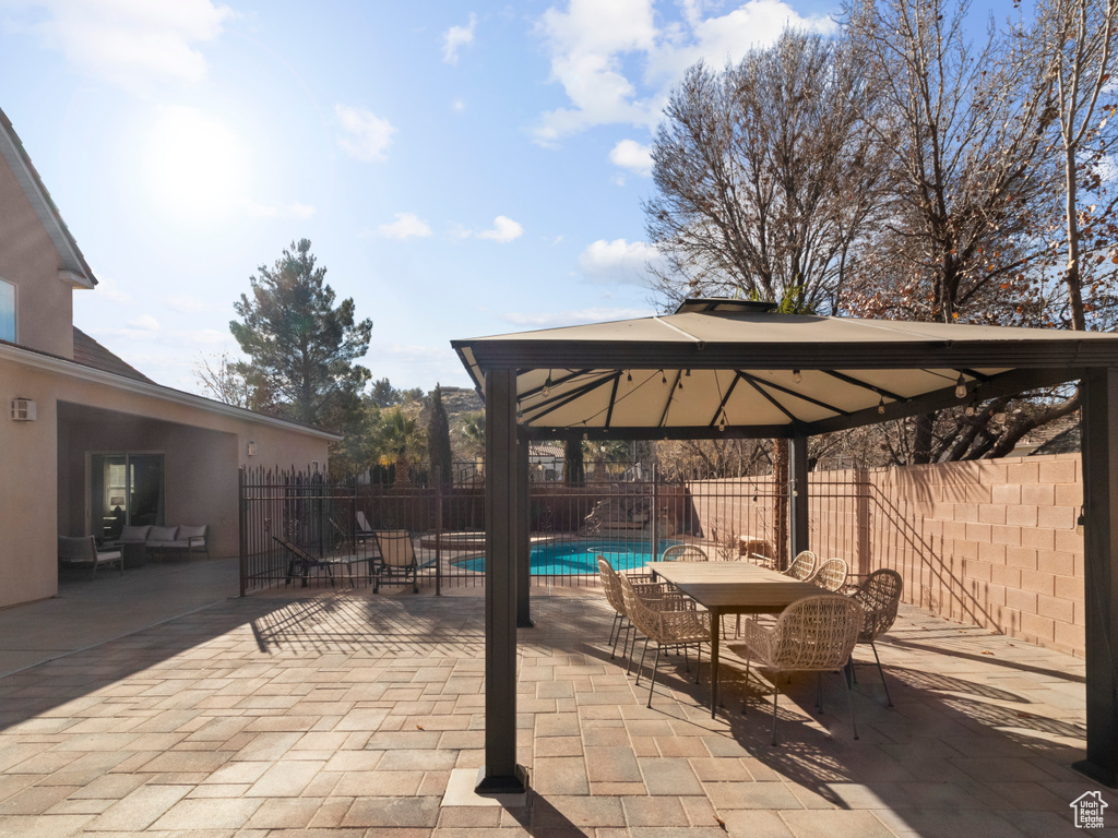 View of patio / terrace with fence, a fenced in pool, a gazebo, and outdoor dining space