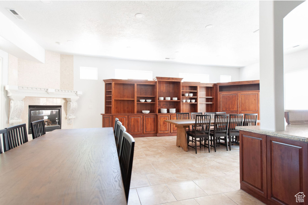Dining area featuring a high end fireplace, visible vents, and light tile patterned floors