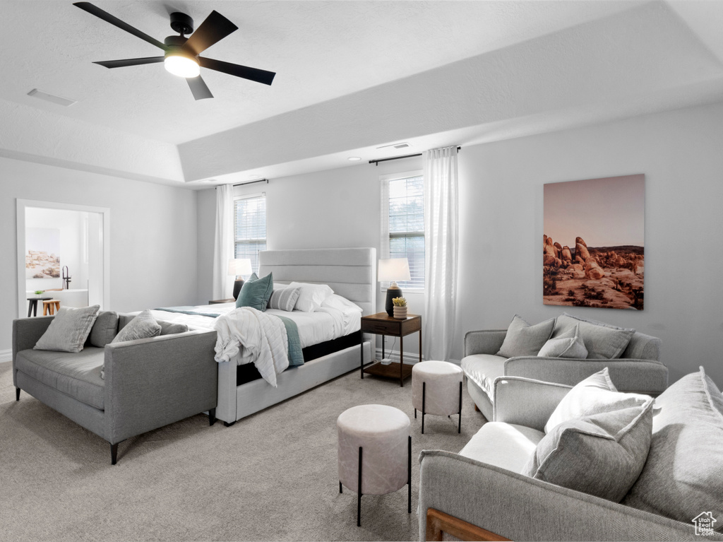 Bedroom featuring a raised ceiling, visible vents, a ceiling fan, and light carpet