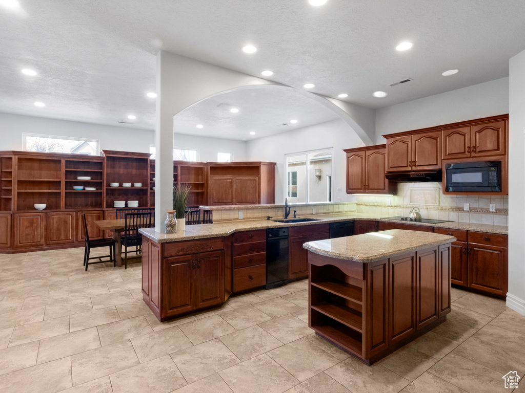 Kitchen with open shelves, arched walkways, black appliances, and a sink