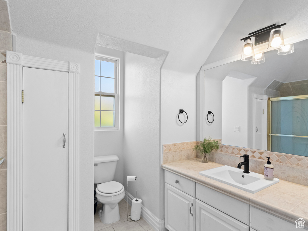Full bathroom with toilet, vaulted ceiling, tile patterned flooring, a shower stall, and vanity