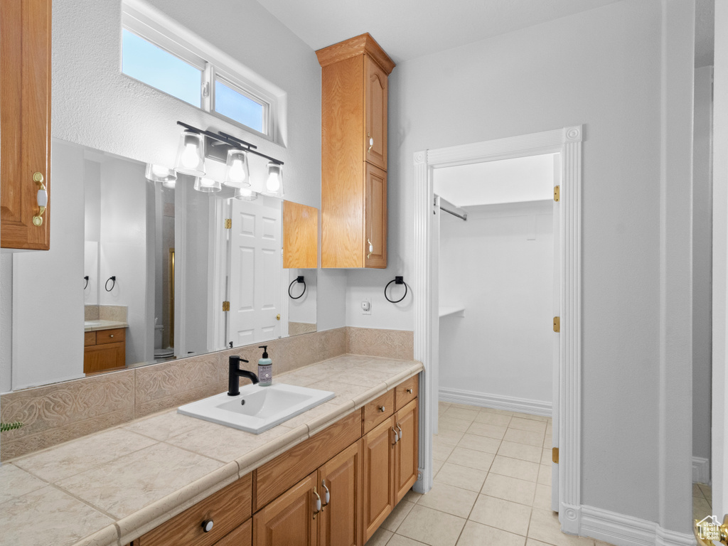 Bathroom featuring baseboards, a spacious closet, tile patterned floors, and vanity