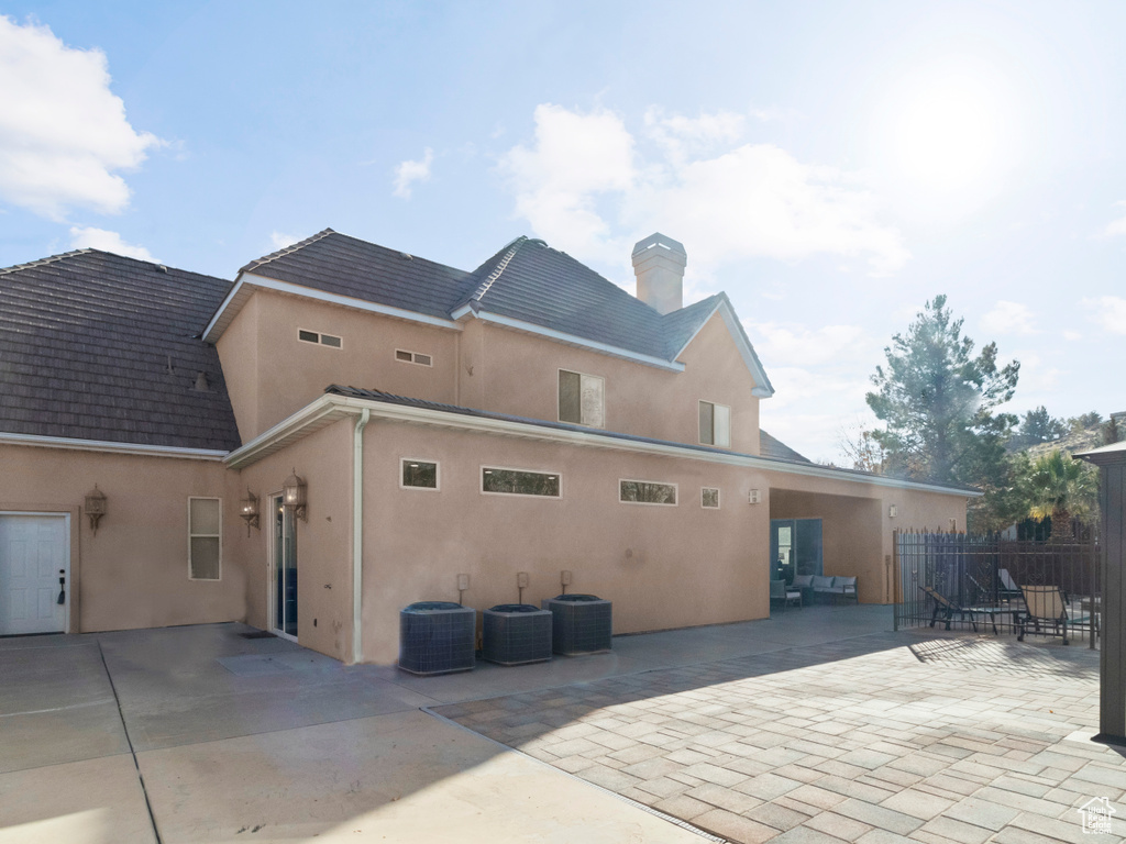 Back of property with central air condition unit, a patio area, stucco siding, and fence