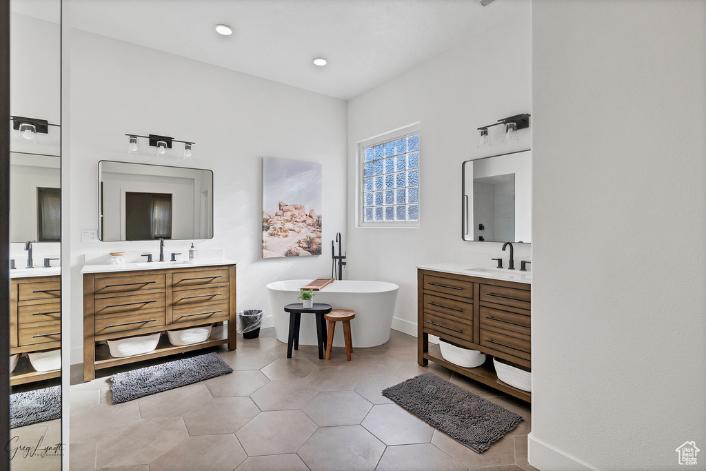 Full bathroom featuring two vanities, a soaking tub, and a sink