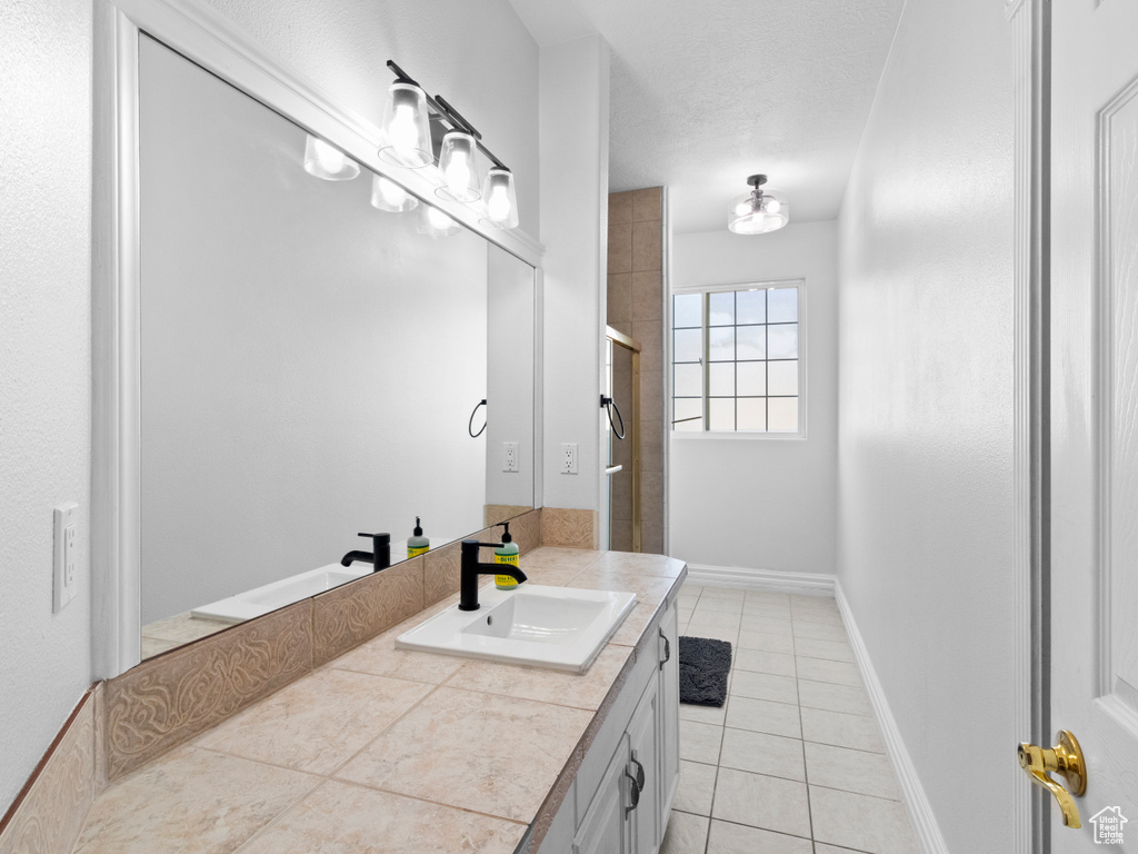 Bathroom with tile patterned flooring, vanity, and a shower with door