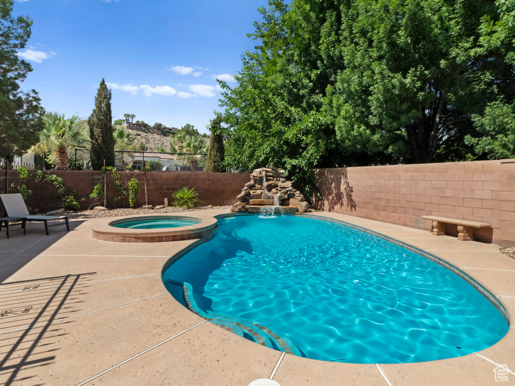 View of swimming pool with a fenced backyard, a pool with connected hot tub, and a patio