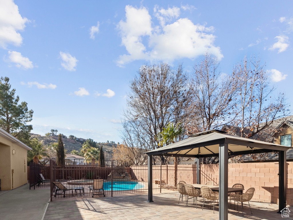 Wooden deck featuring a fenced backyard, a gazebo, a patio area, and a fenced in pool