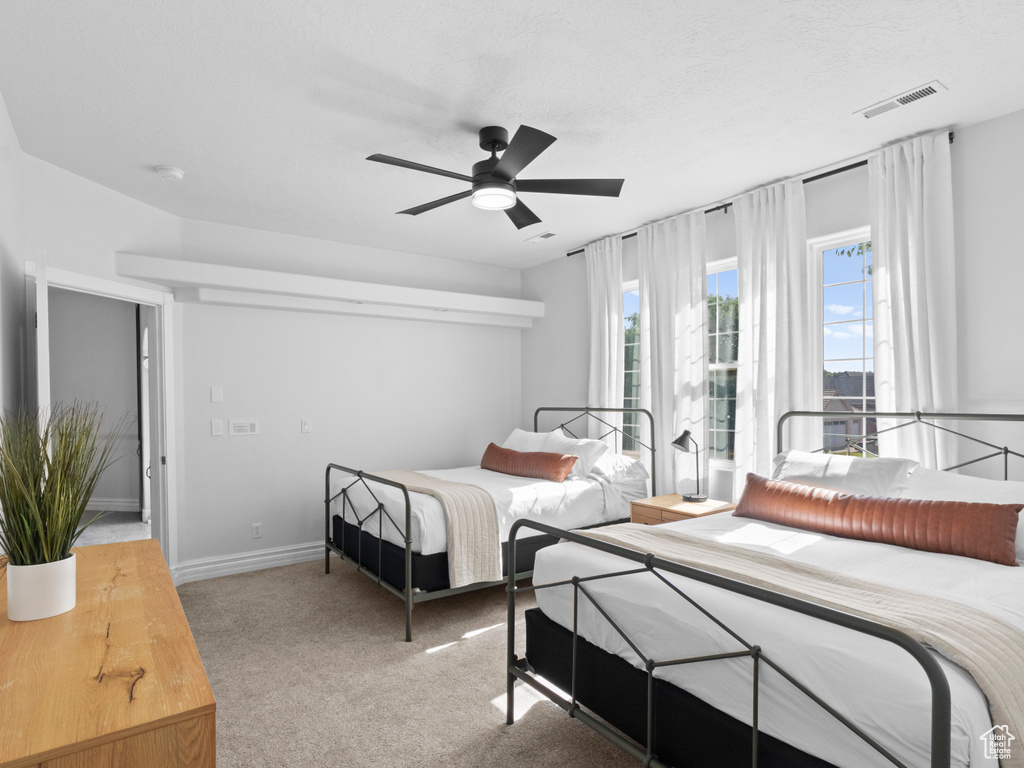 Bedroom featuring ceiling fan, visible vents, and light carpet
