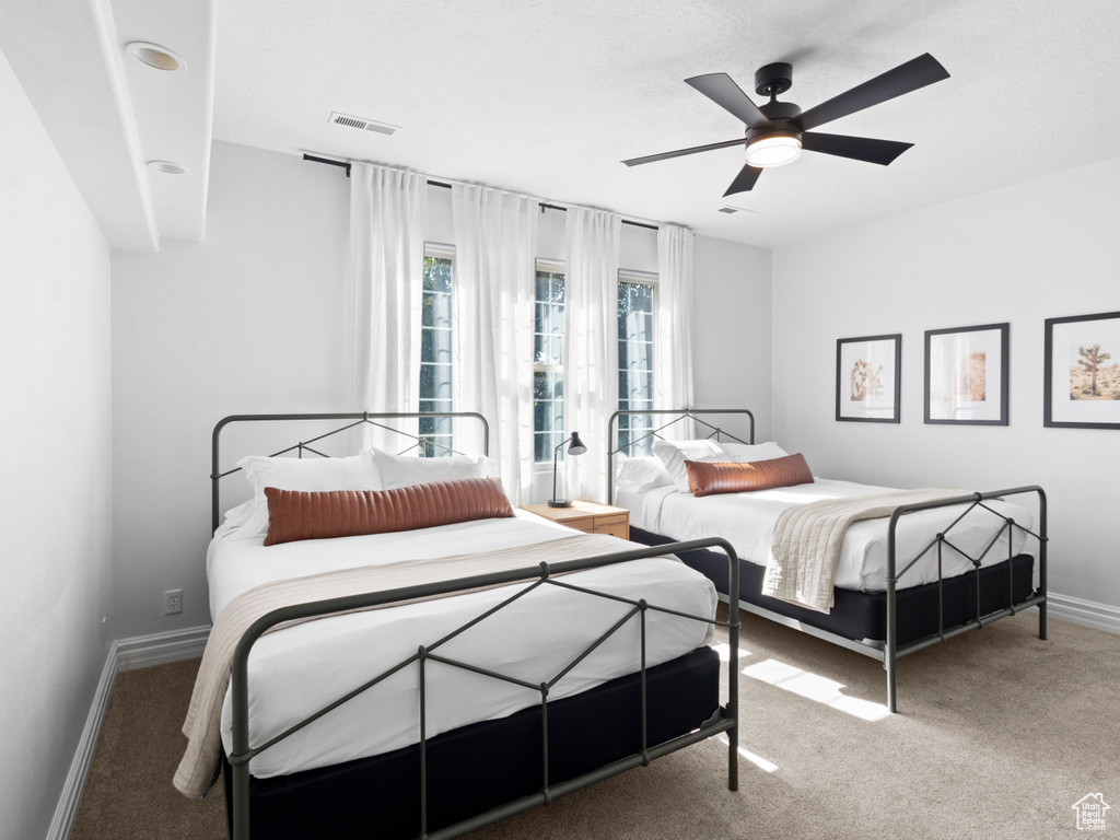 Carpeted bedroom featuring baseboards, a ceiling fan, and visible vents