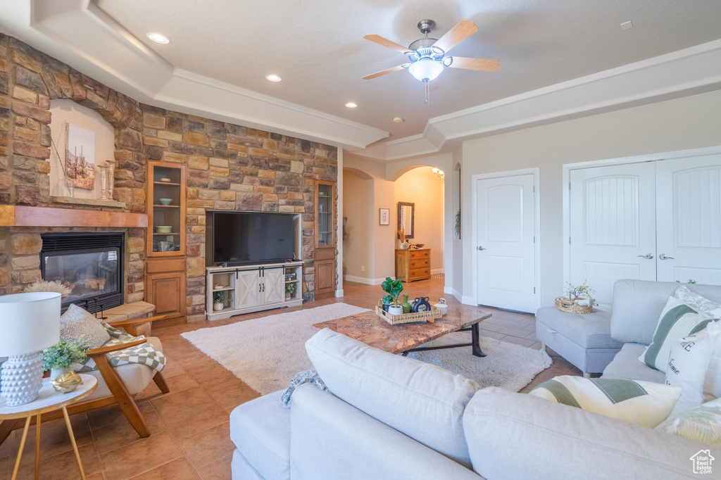 Living area featuring arched walkways, a raised ceiling, a ceiling fan, and light tile patterned flooring