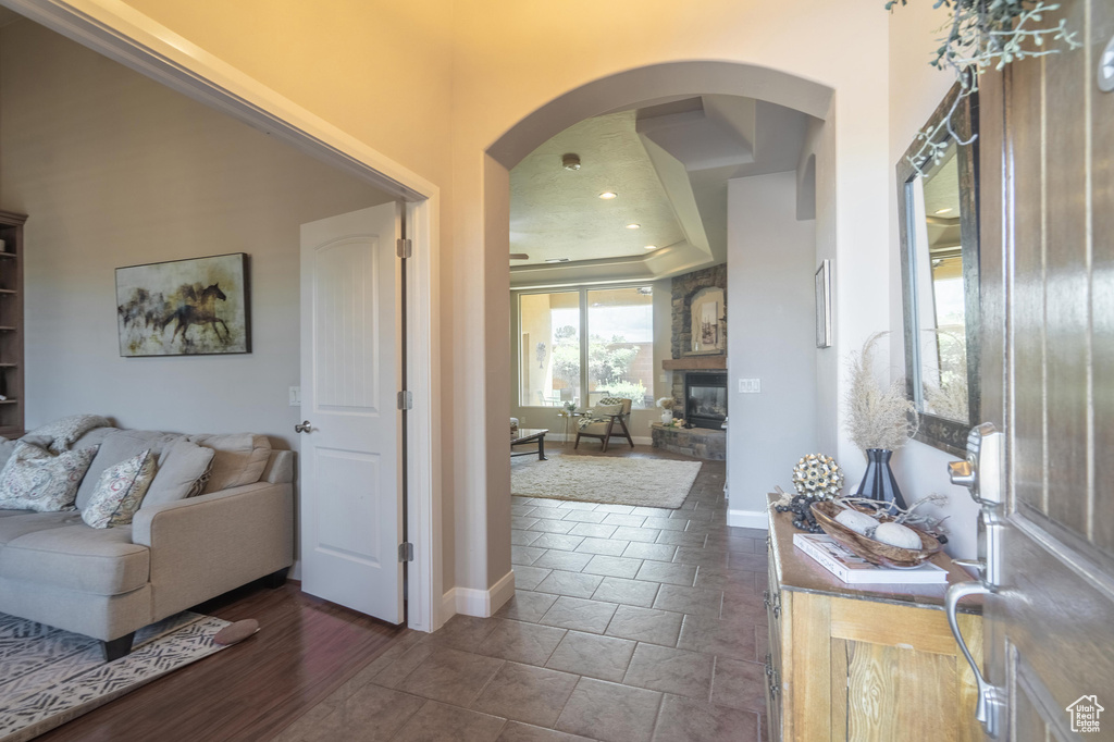 Interior space featuring arched walkways, a stone fireplace, baseboards, and recessed lighting