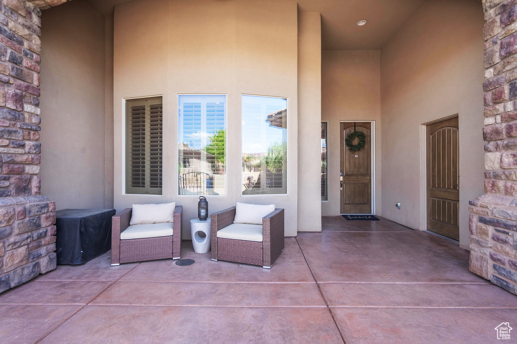 Entrance to property with stone siding, a patio, and stucco siding