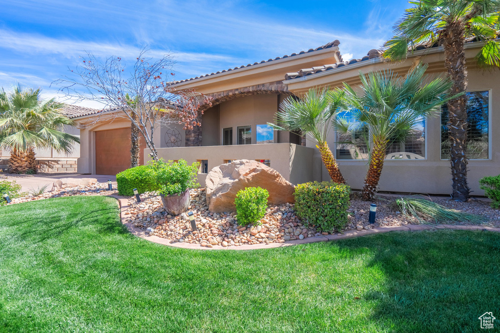 Exterior space featuring a tiled roof, driveway, an attached garage, a yard, and stucco siding