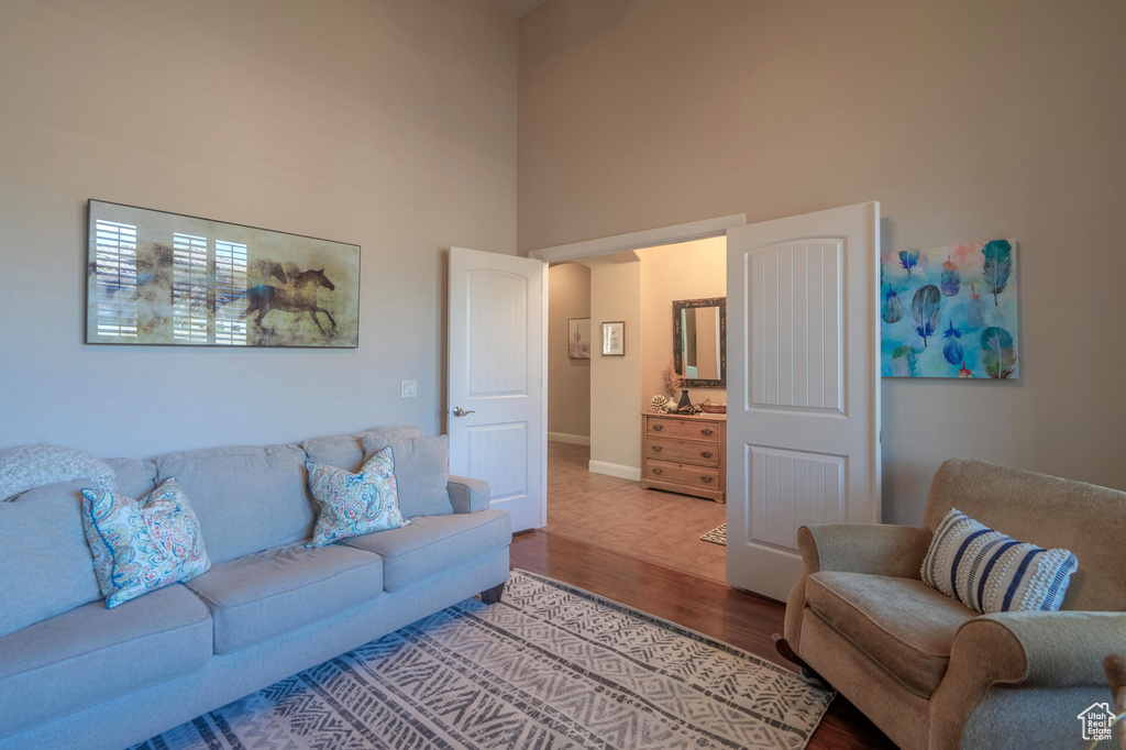 Living area with a high ceiling, wood finished floors, and baseboards