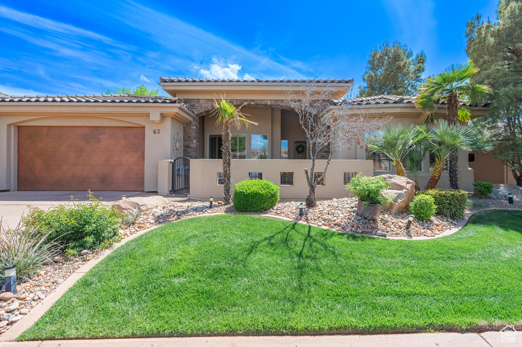 View of front of home featuring a garage, a tile roof, and stucco siding