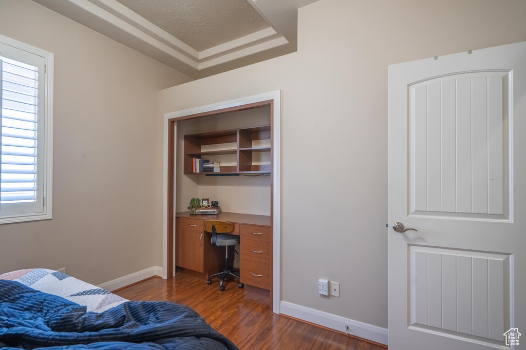 Bedroom with baseboards, dark wood finished floors, a raised ceiling, and multiple windows