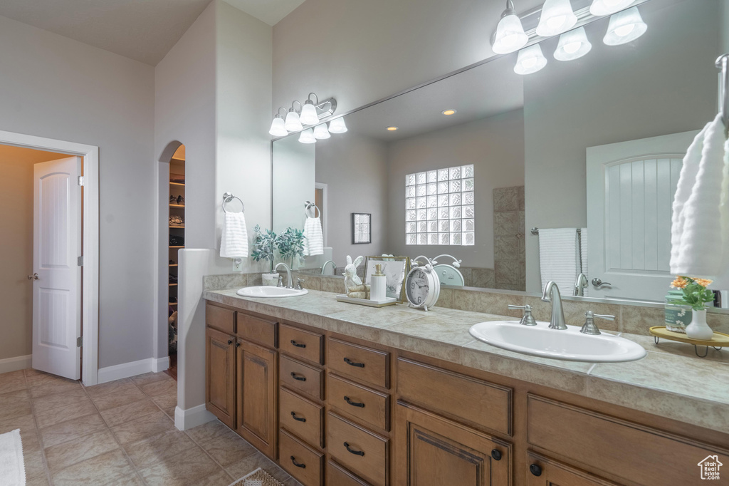 Bathroom with a spacious closet, tile patterned flooring, a sink, and double vanity