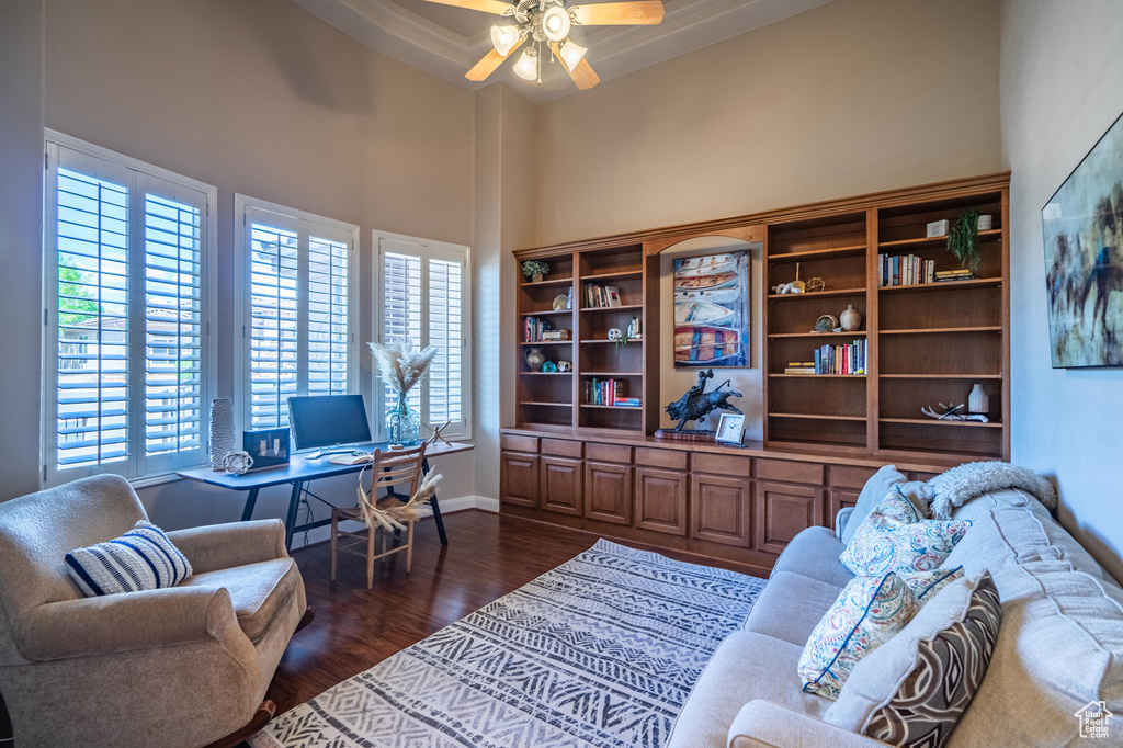 Office with baseboards, a towering ceiling, ceiling fan, and dark wood finished floors