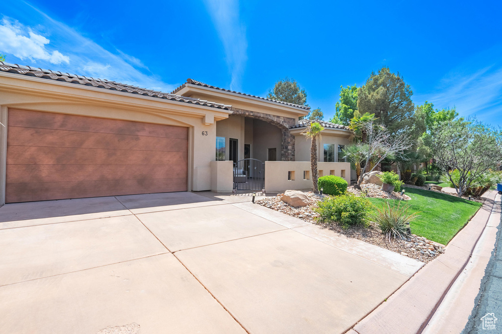 View of front of property featuring a front lawn, driveway, fence private yard, a garage, and stucco siding