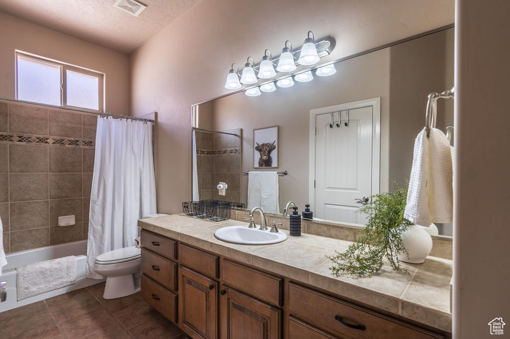 Bathroom with tile patterned floors, visible vents, toilet, vanity, and a textured ceiling