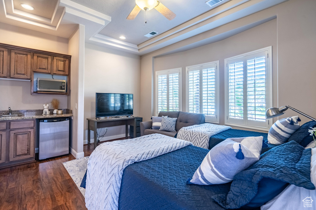 Bedroom with a sink, wet bar, dark wood-style flooring, visible vents, and a raised ceiling