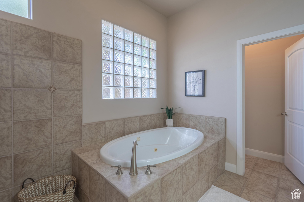 Full bathroom featuring tile patterned floors, a whirlpool tub, and a healthy amount of sunlight