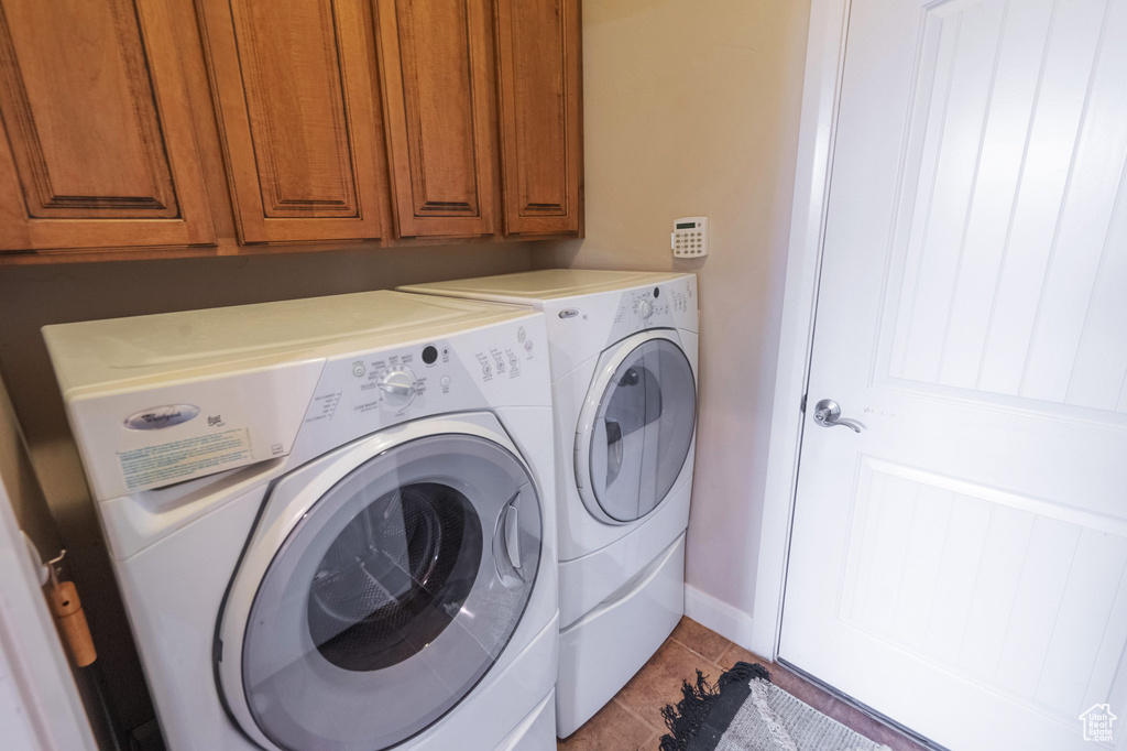 Washroom with baseboards, cabinet space, light tile patterned flooring, and independent washer and dryer