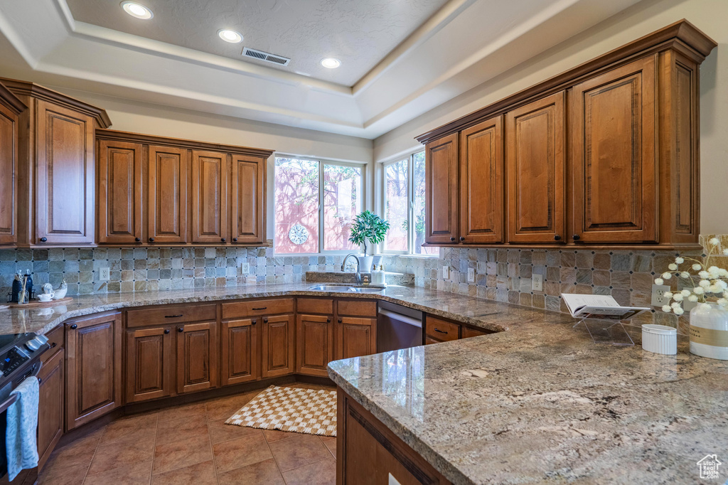Kitchen featuring stainless steel appliances, a tray ceiling, visible vents, a sink, and brown cabinetry