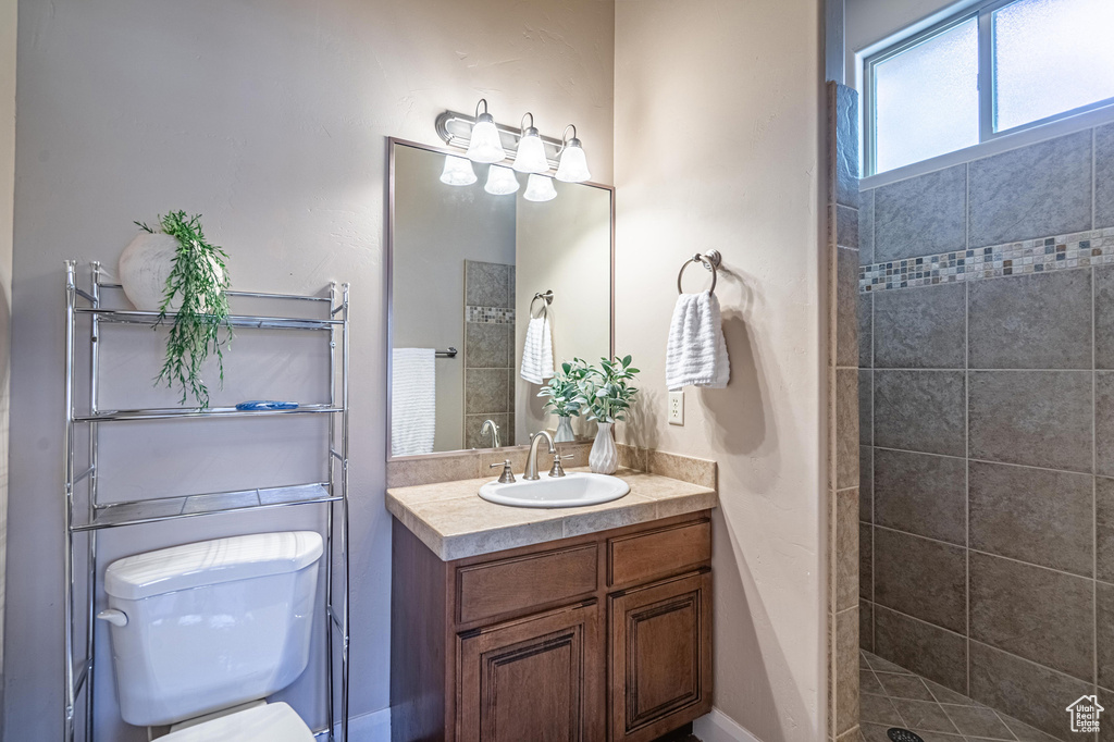 Bathroom with toilet, vanity, and tiled shower