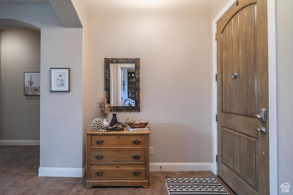 Foyer featuring tile patterned floors, baseboards, and arched walkways