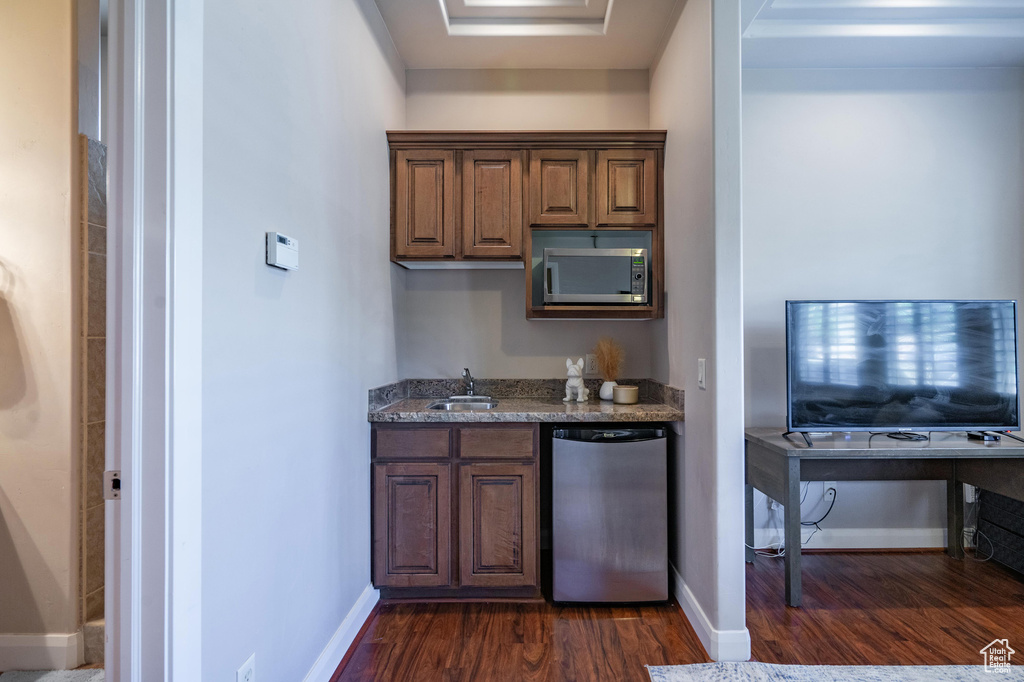 Bar with a sink, fridge, indoor wet bar, baseboards, and dark wood-style flooring