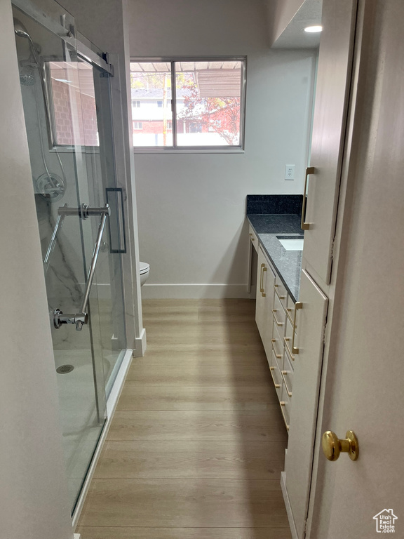 Full bath with a shower stall, toilet, wood finished floors, vanity, and baseboards