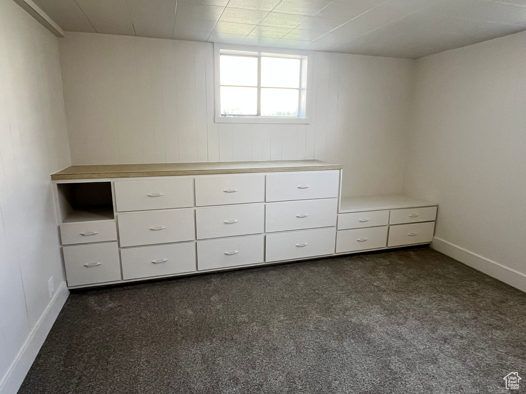 Interior space featuring dark colored carpet and baseboards