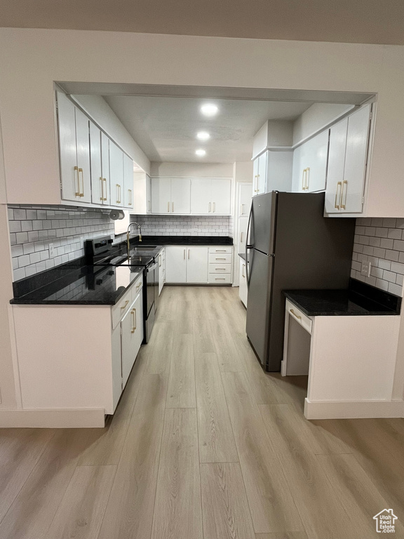 Kitchen featuring decorative backsplash, dark countertops, light wood-style floors, and white cabinets