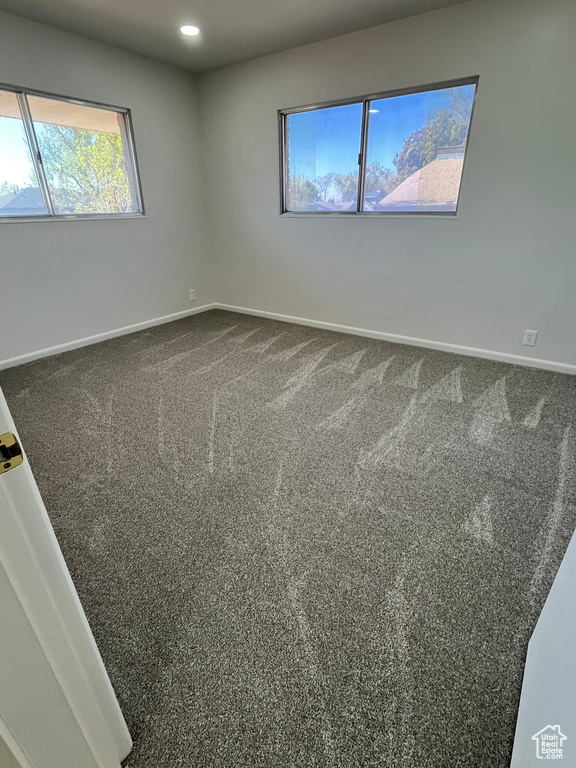 Spare room with dark colored carpet, baseboards, and recessed lighting