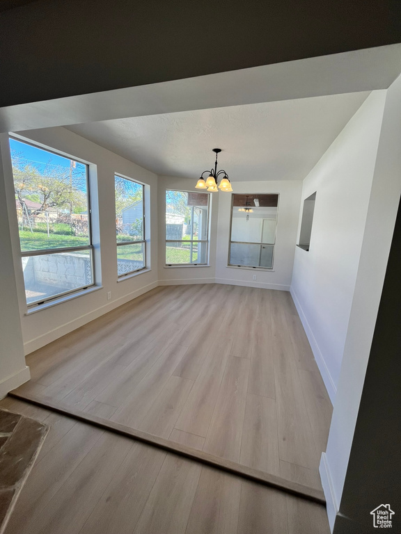 Interior space featuring an inviting chandelier, light wood-style floors, and baseboards
