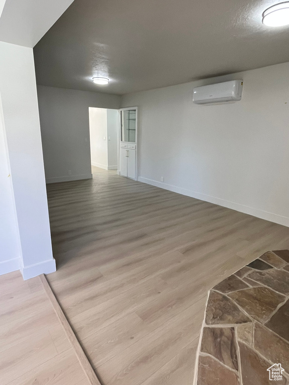 Empty room with baseboards, wood finished floors, and an AC wall unit