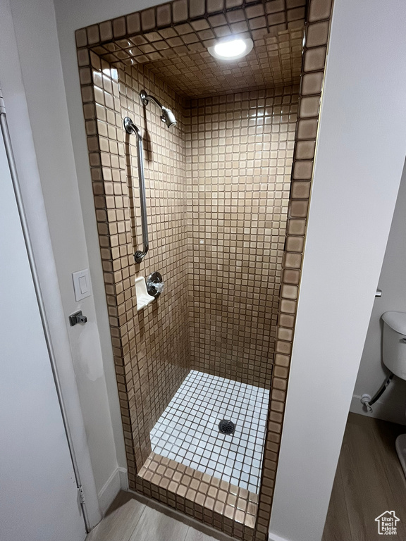 Full bath featuring baseboards, toilet, wood finished floors, and a stall shower